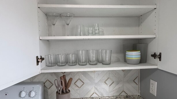 Una cocina con gabinetes blancos, encimera de granito y estufa.