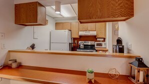 Eine Küche mit Holzschränken, einem Kühlschrank, einem Herd, einer Mikrowelle und einem Spülbecken.