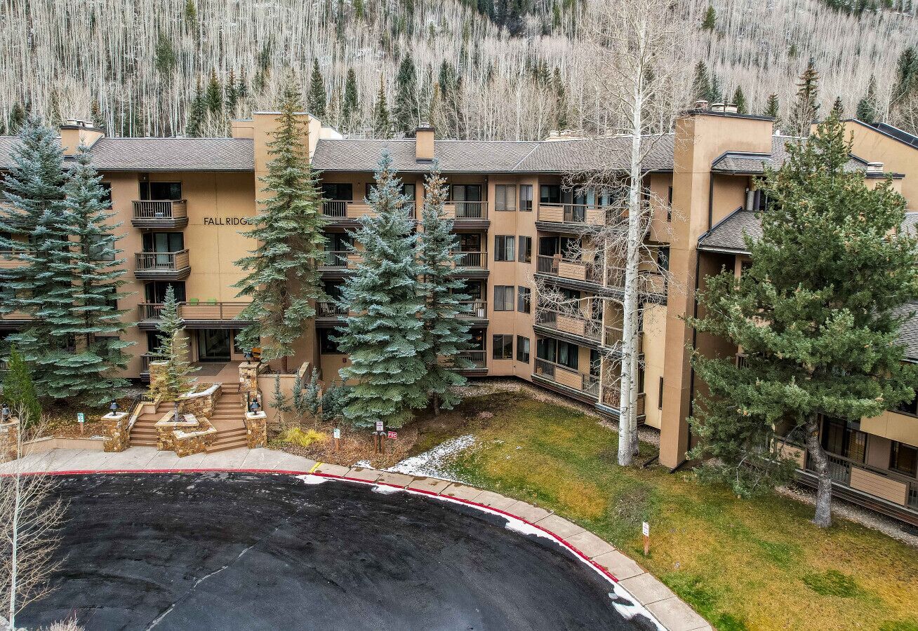 Un hôtel à plusieurs étages doté d’une cour intérieure, entouré d’arbres et ayant une chaîne de montagnes en toile de fond.
