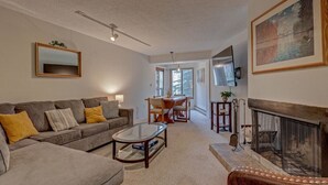 Ein Wohnzimmer mit Sofa, Couchtisch, Kamin und einem Essbereich mit Tisch und Stühlen.
