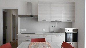 A modern kitchen with white cabinets, a stainless steel oven, and a dining table with a colorful table runner. - SE202 - Senigallia, new, fully equipped three-room apartment in the city center (Senigallia)