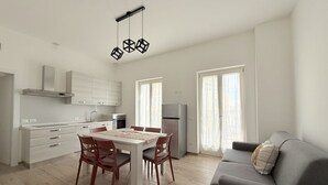 A modern kitchen with a dining table, chairs, and a grey sofa. - SE202 - Senigallia, new, fully equipped three-room apartment in the city center (Senigallia)