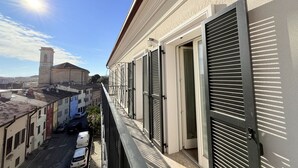 A balcony with a view of a street, a building with shutters, and a tower in the background. - SE202 - Senigallia, new, fully equipped three-room apartment in the city center (Senigallia)