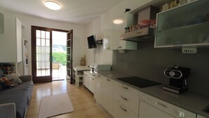 Una cocina moderna con armarios blancos, horno empotrado y un amplio ventanal.