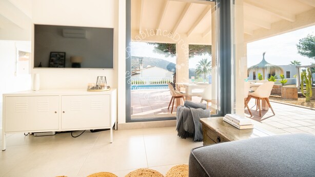 Een moderne woonkamer met een witte kast, een bank en een eethoek met stoelen.