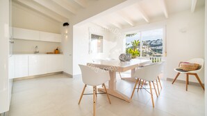 Een lichte, moderne keuken met witte kastjes en een groot raam met uitzicht op een prachtig landschap.
