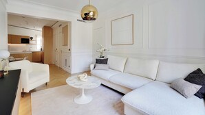 A modern living room with a white sofa, a round coffee table, and a kitchen in the background. - Elegant A/C Apt 2br/6p - Paris 17th/monceau (Paris)