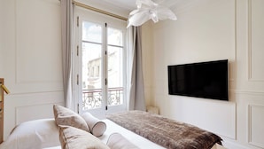 A hotel room with a bed, a television mounted on the wall, and a window with curtains. - Elegant A/C Apt 2br/6p - Paris 17th/monceau (Paris)