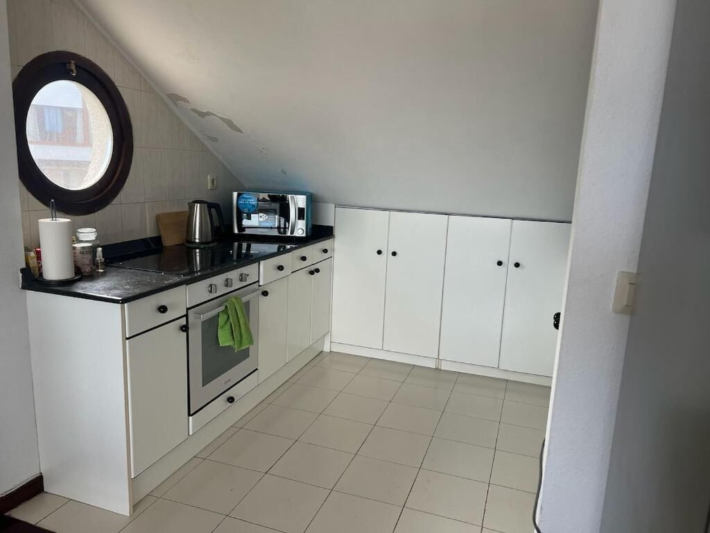 A kitchen with white cabinets, a stove, a sink, and a coffee maker.