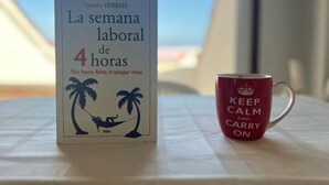 Pöydällä, punaisen mukin vieressä, on kirja nimeltä ”La semana laboral de 4 horas”, jonka on kirjoittanut Timothy Ferriss. Mukissa on teksti: ”KEEP CALM AND CARRY ON”.