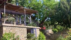 Un bâtiment en pierre doté d’un balcon, de plantes en pot et d’un mur en pierre.