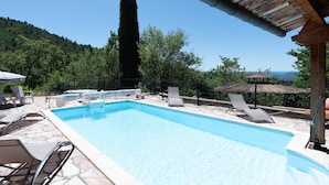 Une piscine rectangulaire à l’eau d’un bleu limpide, entourée de carreaux de pierre et dotée de chaises longues.