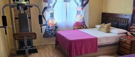 A bedroom with a bed, a desk, a chair, a window with curtains, and a ceiling fan.