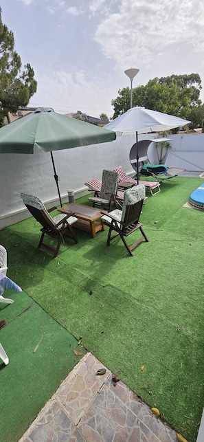 An outdoor seating area with artificial grass, wooden furniture, and umbrellas. - Villa Noa. (Torrevieja)