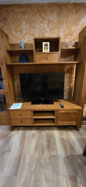 Eine Holzunterhaltungsecke mit Flachbildfernseher, Schubladen und Regalen.