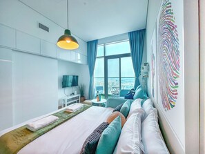 A modern hotel room with a large bed, a TV, a balcony with a view, and a decorative wall piece. - Minimal Studio in Marina (Dubai)