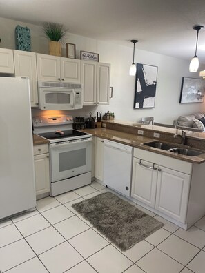 A kitchen with white cabinets, a microwave, stove, dishwasher, and granite countertops. - Green links -Lely Resort 2 Bdrm, 2 bath condo (main floor with many amenities) (Naples)
