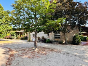 Ein Gebäude aus Stein mit einem Garten, einem gepflasterten Weg und einem Baum im Vordergrund.