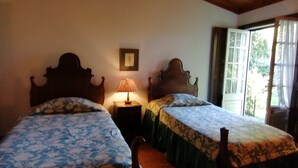 A room with two wooden beds, a nightstand with a lamp, a framed picture on the wall, and a window with curtains. - Fabulous farm in Mesquitela, Mangualde for vacation with pool for 18 people (Mesquitela)
