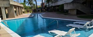 Piscina com espreguiçadeiras e um edifício de design moderno.