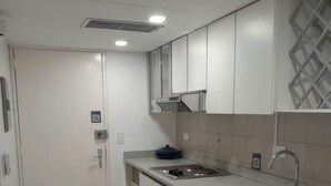 A modern kitchen with white cabinets, a stainless steel sink, and a built-in stove. - Studio in Zona Top, steps from the beach (Near City Place and La Vela) (Pampatar)