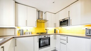 A modern kitchen with white cabinets, a gas stove, an oven, and a microwave. - Peaceful London City Apartment & Free Parking (London)