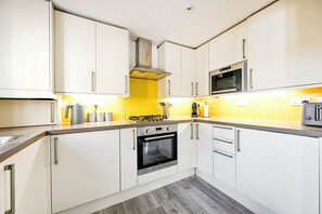 Eine moderne Küche mit weißen Schränken, einem Gasherd, einem Backofen und einer Mikrowelle.