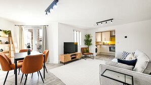 A modern living room with a dining area, a TV, and a sofa. - Peaceful London City Apartment & Free Parking (London)