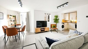 A modern living room with a dining area, a TV, and a kitchen. - Peaceful London City Apartment & Free Parking (London)