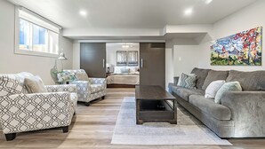 Una sala de estar moderna con un sofá, sillones, una mesita de centro y un cuadro en la pared.