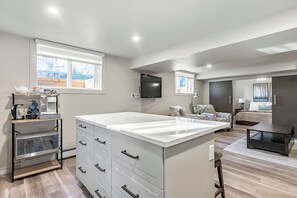 Een moderne keuken met een groot eiland, ingebouwde apparatuur en een eethoek met een bank en salontafel.