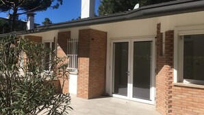 En bostadsbyggnad med en fasad av tegel, en täckt uteplats och en stor skjutdörr av glas.