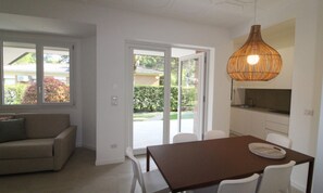 Eine moderne Küche mit Esstisch und Stühlen, einer Couch und einem großen Fenster mit Blick nach draußen.