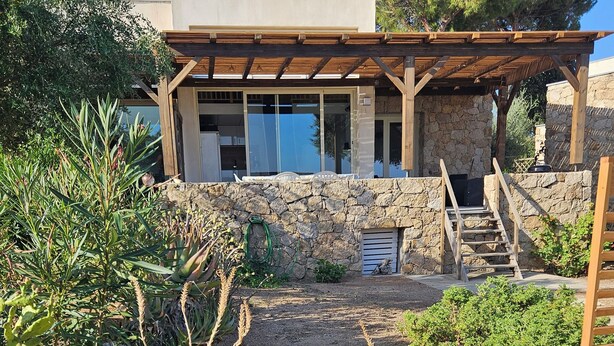 A modern house with a stone wall, a wooden pergola, and a garden with various plants. - House in the Marine di Sant'Ambroggio, 10-minute walk to the sea, large terrace (Lumio)