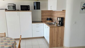 A compact kitchen with white cabinets, a microwave, a toaster, and a coffee maker. - House in the Marine di Sant'Ambroggio, 10-minute walk to the sea, large terrace (Lumio)