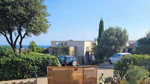 A residential area with a paved driveway, a wooden gate, and a car parked in the driveway. - House in the Marine di Sant'Ambroggio, 10-minute walk to the sea, large terrace (Lumio)