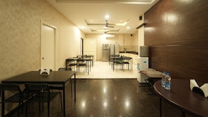 A hotel room with a dining area, kitchenette, and a door leading to another room. - SHIVOM RESIDENCY (Hyderabad)