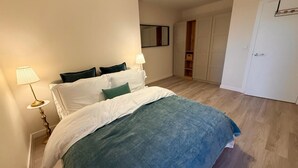 A bedroom with a bed, bedside lamps, a wardrobe, and a door. - White City Luxury | 1BR Apartment | Prime Location (London)