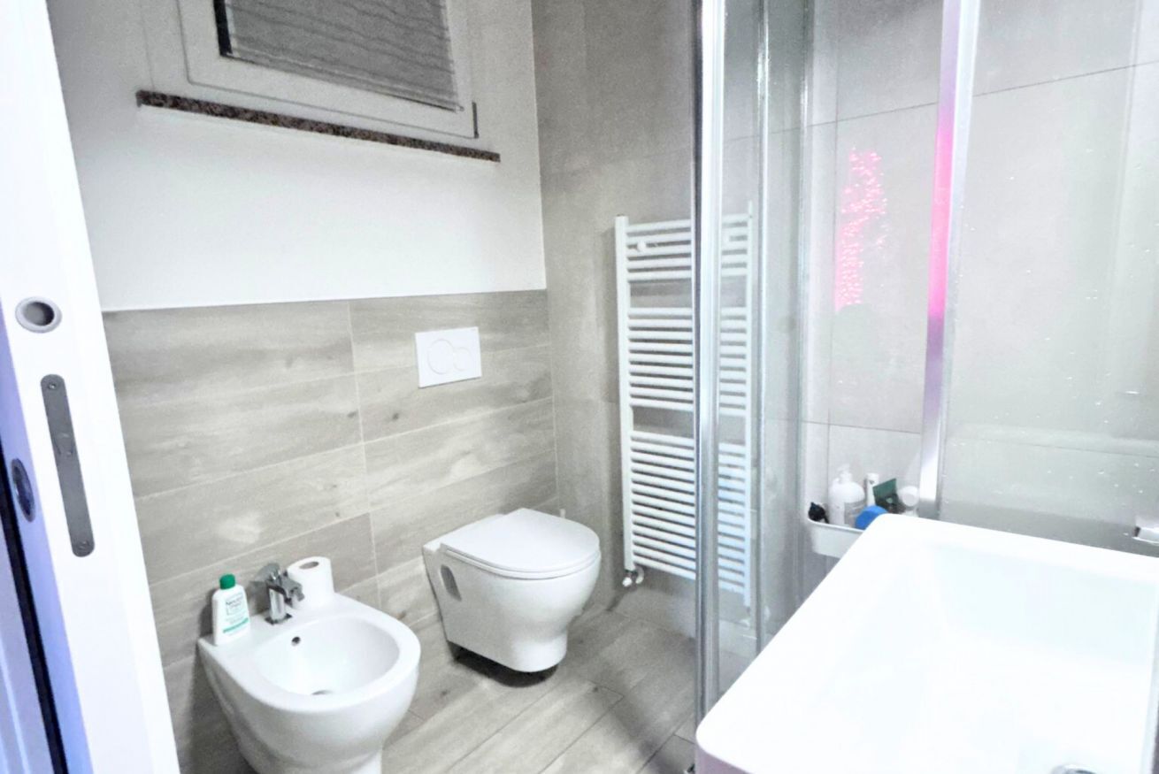 A bathroom with a bidet, toilet, and a glass shower enclosure.