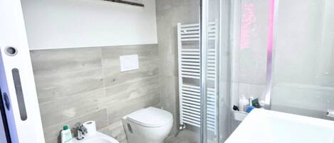 A bathroom with a bidet, toilet, and a glass shower enclosure.