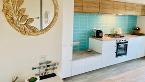 Una cocina moderna con armarios blancos, salpicadero azul y un espejo redondo con diseño de hojas.