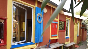 A colorful building with a wooden deck, a bench, and a statue.