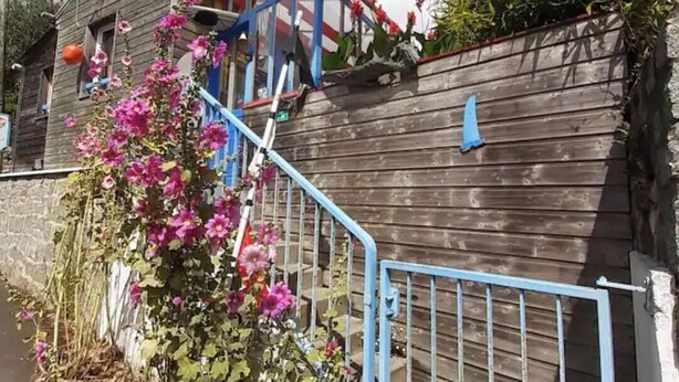 A wooden house with a blue metal staircase leading to a porch.