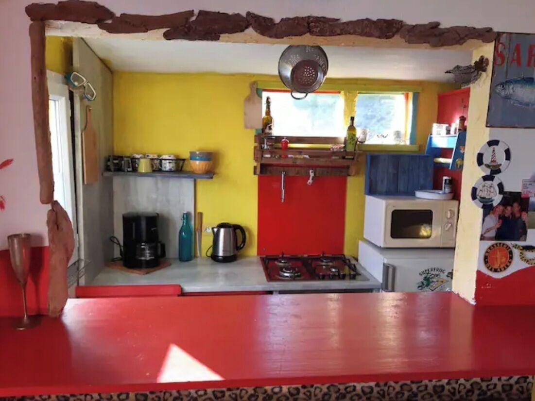 A kitchen with a red countertop, a stove, a microwave, and a window with a view.