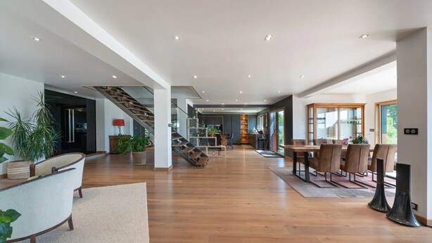Un vaste espace de vie comprenant un escalier, un plancher en bois et un coin repas avec des chaises et une table.
