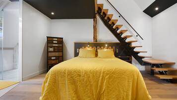 Quarto com uma cama grande, penteadeira de madeira e escada.
