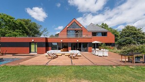 Une maison moderne dotée d’une terrasse, d’un espace salon extérieur et d’une piscine.