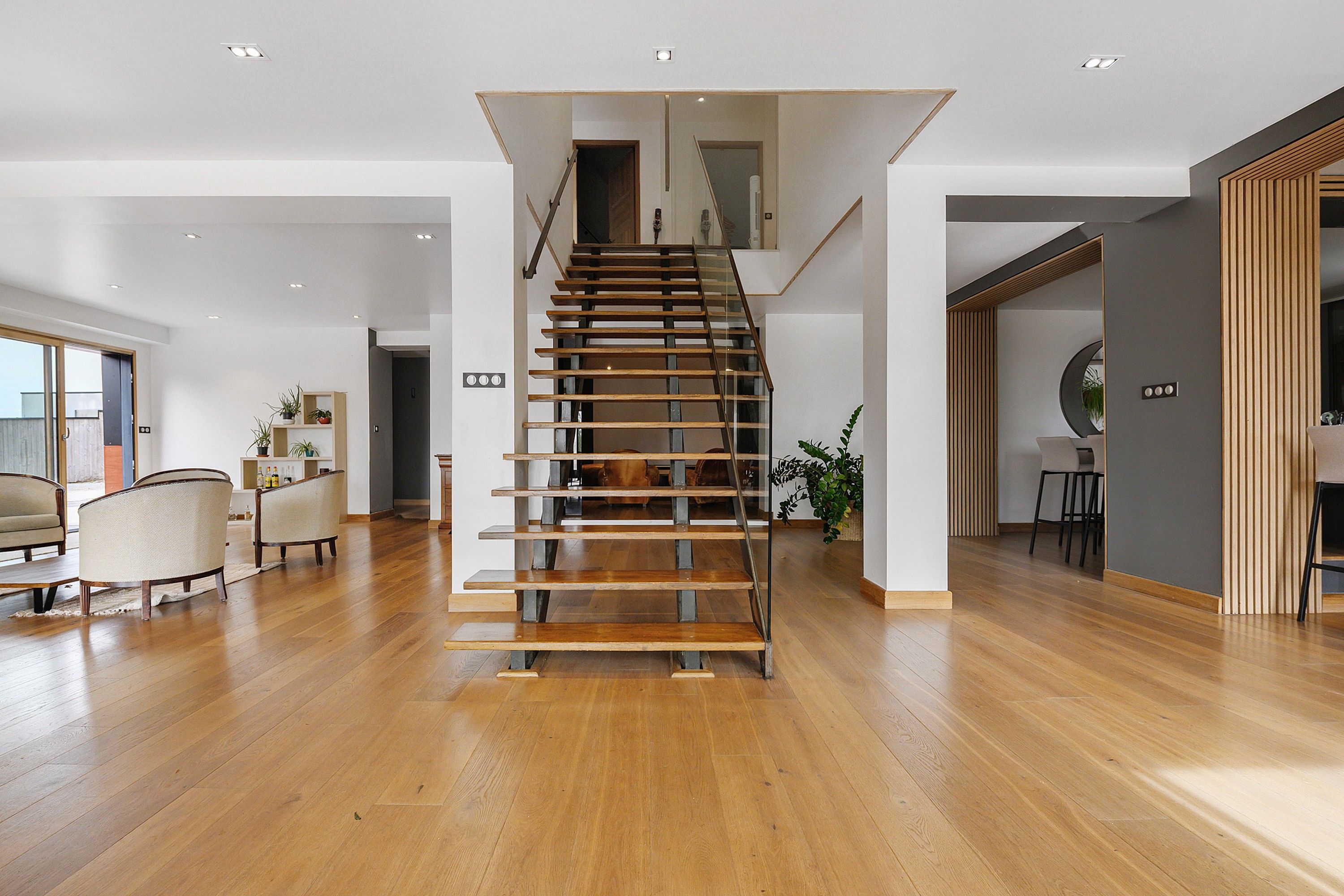 Amplia sala de estar con una escalera de madera que conduce a un piso superior.