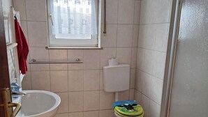 A small bathroom with a sink, toilet, and window. - Cozy vacation apartment at the Hainerhof (Grünberg)
