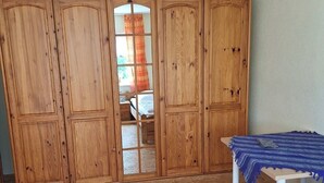 A bedroom with a wooden wardrobe, a bed with a blue blanket, and a wooden floor. - Cozy vacation apartment at the Hainerhof (Grünberg)